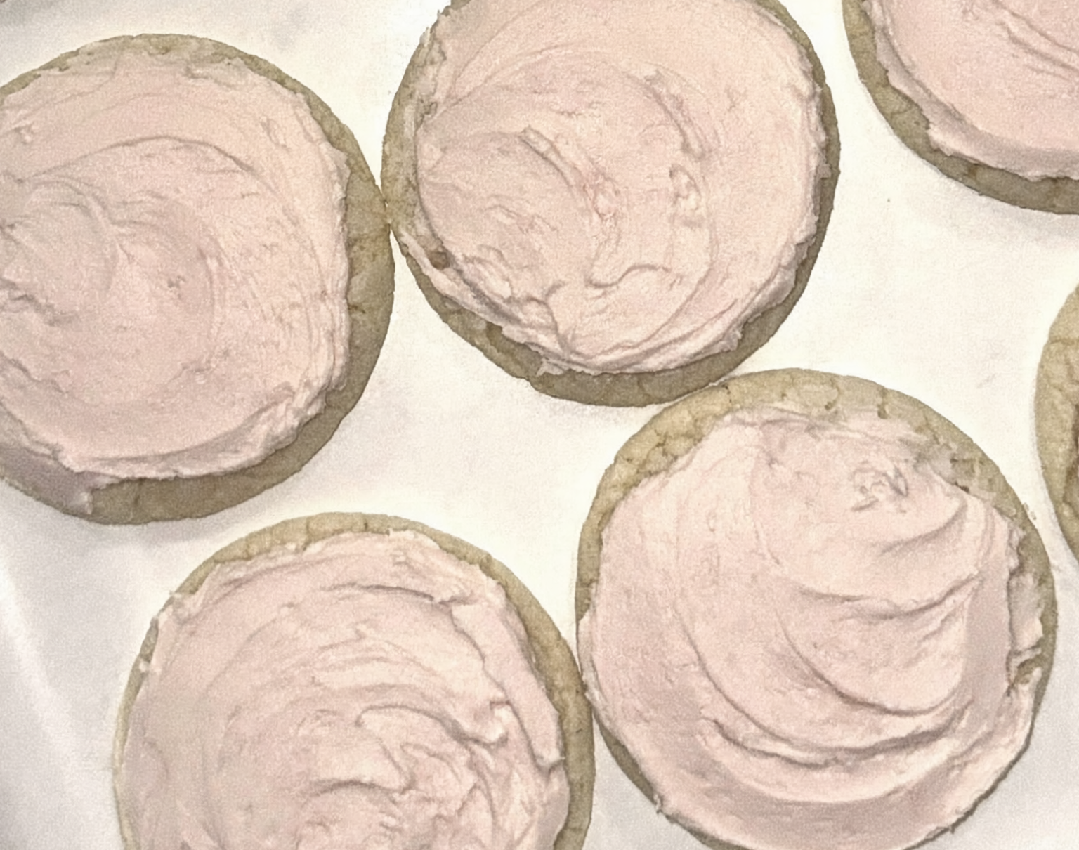 Cookies with pink frosting on a baking sheet